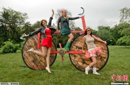 图为女孩骑在大木自行车模型上。