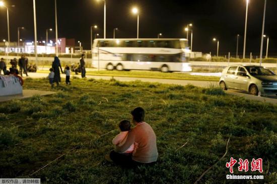 一名叙利亚难民与她的孩子坐在高速路车站的草地上。国际移民组织发布的最新数据显示，前往欧洲的难民数量依然居高不下，今年以来已有超过10万人经由地中海前往希腊，7500人经由地中海前往意大利。
