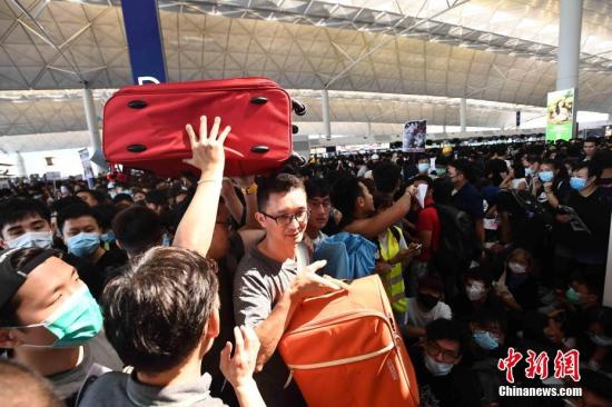 8月12日下午3时许，大批非法集结于香港国际机场的示威者拆走铁马，进入原先只限持机票旅客才可进入的离境大堂禁区前通道位置。受非法集结影响，大批登机旅客受阻，航班取消。中新社记者